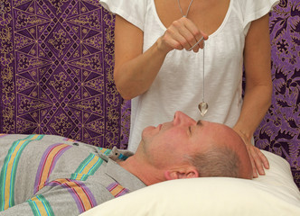 Therapist dowsing a patient's third eye chakra