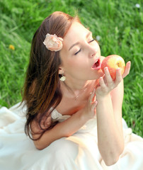 brunette young girl with an apple in summer park
