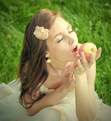 brunette young girl with an apple in summer park enjoying