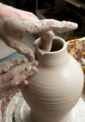 hands of a potter, creating an earthen jar on the circle