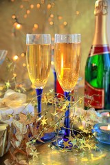 Champagne in glasses,candle and lights on gold background.