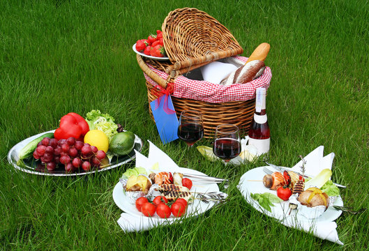 Picnic basket with different food on grass