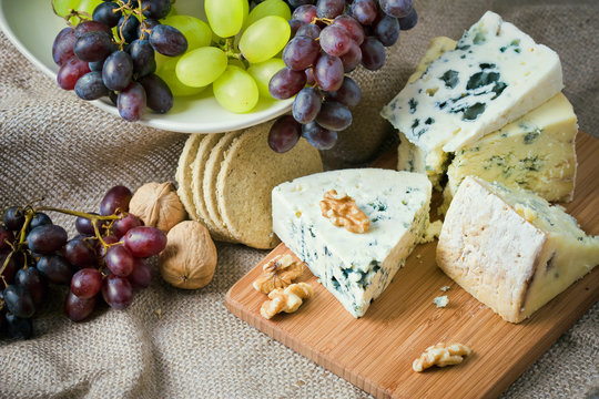 Cheese still life with red grapes, walnuts and crackers
