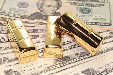 drei Goldbarren auf Dollarscheinen
