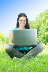happy young woman using laptop computer outdoors