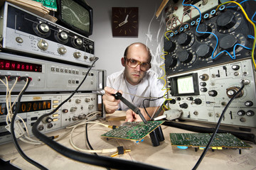 Funny nerd scientist soldering at vintage laboratory