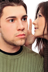 Closeup portrait of young couple of students. Woman whispering s