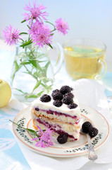 Bouquet of cornflowers and piece of cake with black raspberry