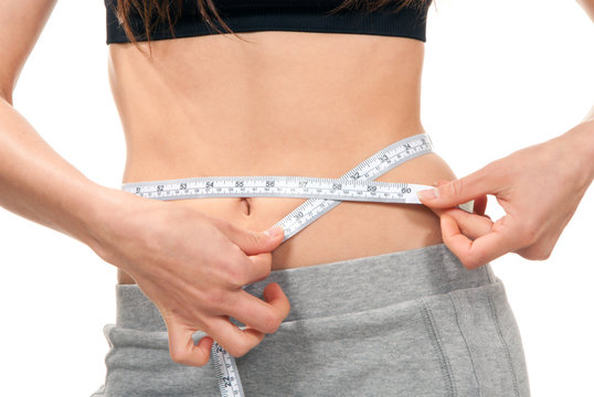 Athletic fit slim female measuring her waist metric tape measure