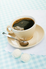 black coffee with coconut candies on a blue tablecloth