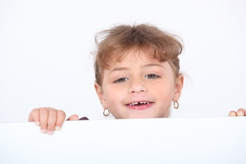 little blonde girl laughing is half hidden behind a white panel