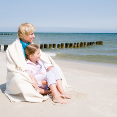 Happy childhood - little girl with mother  on the beach
