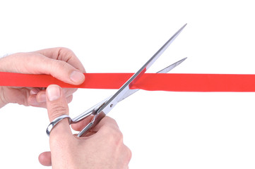 Closeup of a mans hand cutting a red ribbon with scissors
