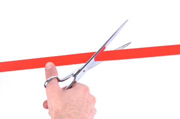 Closeup of a mans hand cutting a red ribbon with scissors