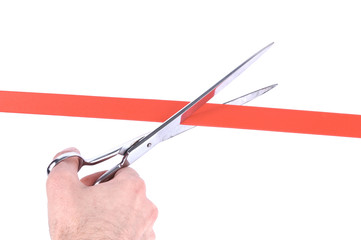 Obraz premium Closeup of a mans hand cutting a red ribbon with scissors