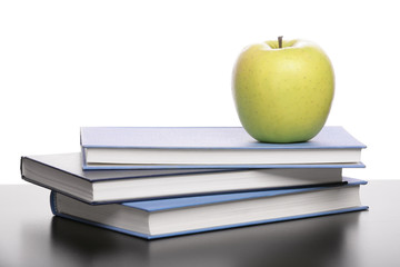 Three books and apple on the desk