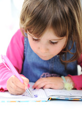 Happy little girl drawing with pencils at home