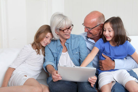 Senior people with grandkids using electronic tablet