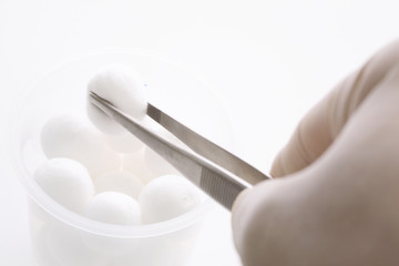 消毒綿をピンセットでつかむ医者の手元