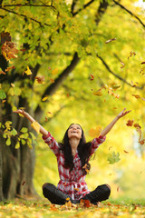 woman drop leaves in autumn park