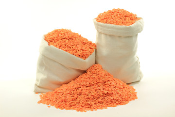 Red lentils in bags and on pile.
