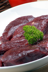 rohes Straussensteak mit Petersilie auf einem Teller