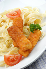 Fischstäbchen mit Bandnudeln auf einem Teller