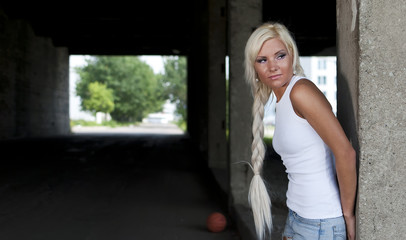 Obraz premium girl in denim shorts and white T-shirt standing at the pillar