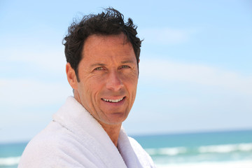 Man stood at the beach wearing bath robe