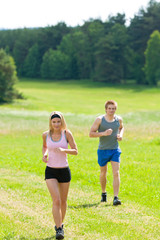 Sportive young couple jogging meadows sunny summer