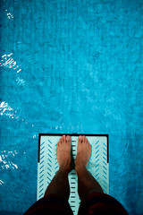 feet on diving board over pool