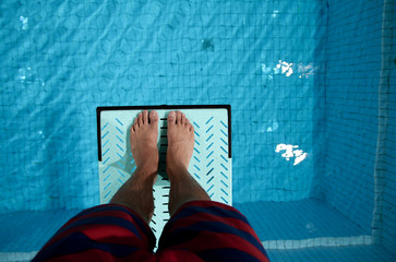 feet on diving board over pool - 33787354