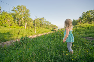 Naklejka na ściany i meble Adorable toddler girl stay on hill and look to ongoing train