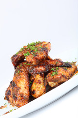 Hot grilled chicken wings on white plate with drizzle of sauce