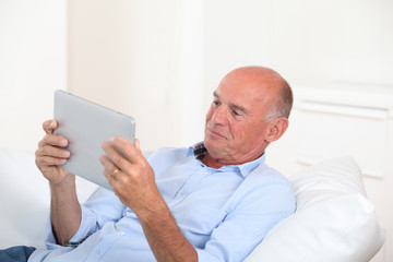 Naklejka premium Senior man using electronic tablet at home