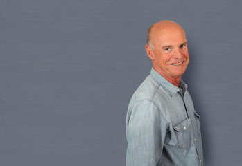 Portrait of senior man standing on grey background