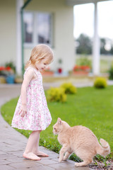 Adorable happy preschooler girl and a cat outdoors