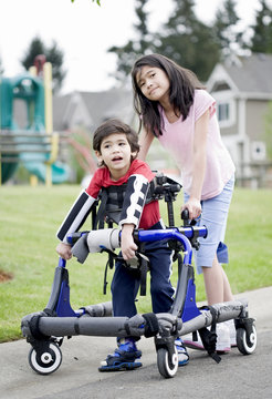 Big sister helping younger disabled brother in walker