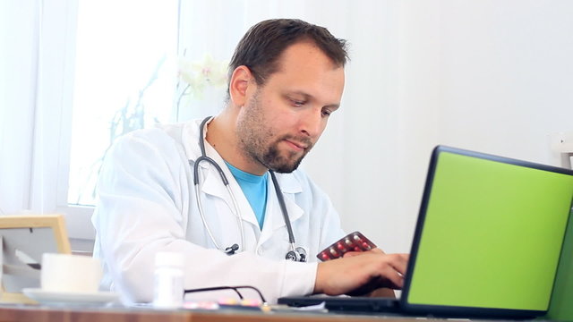 Male doctor working on computer and checking medications