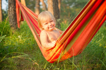 Adorable baby girl sit and smile relaxing in hammock