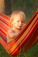 Fototapeta na wymiar Adorable baby girl sit and look around relaxing in hammock