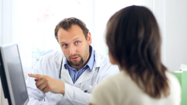 Male doctor explaining something on computer to female patient