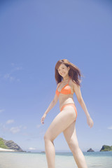 Naklejka premium 波打ち際を歩く水着女性