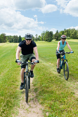 Fototapeta na wymiar Sport couple riding mountain bicycles in coutryside