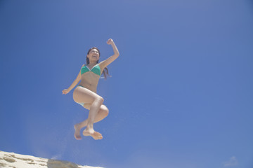 砂浜でジャンプする水着女性
