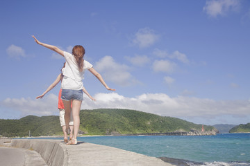 Obraz premium 海辺の防波堤を歩く女性2人の後ろ姿