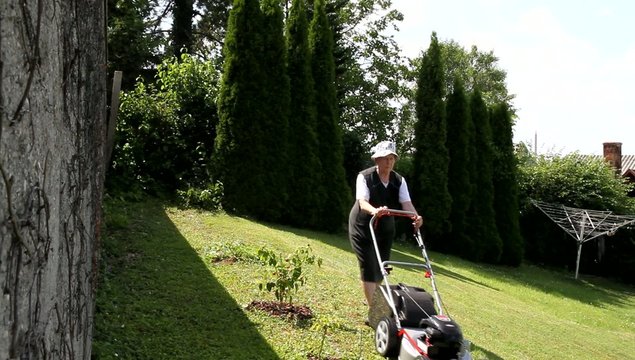 R&uuml;stige betagte Dame beim Rasenm&auml;hen
