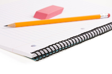 Pencil and eraser laying on notebook on white background