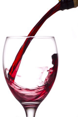 Red wine being poured into a glass, white background.