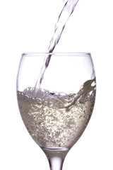 White wine being poured into a glass, white background.
